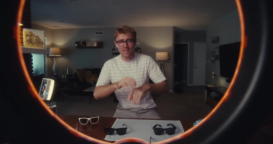 Man playfully enters the area near a ring light and talks about glasses