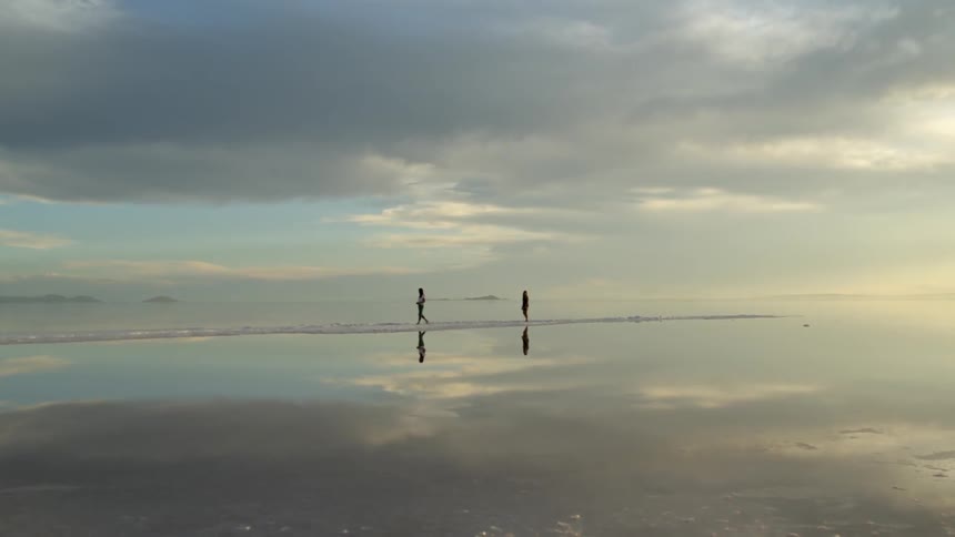 Two people walk along the shoreline