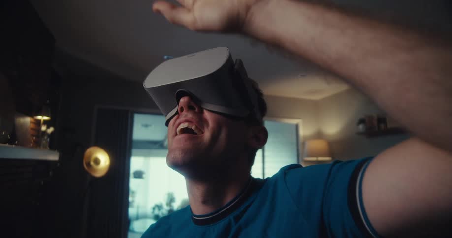 Cheerful man using virtual reality glasses while standing in a living room