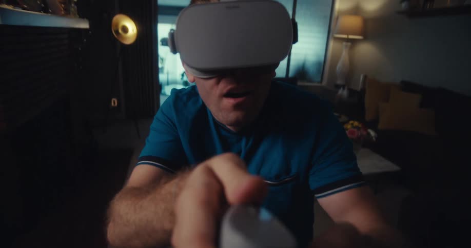A man swings the controller as he uses a virtual reality headset