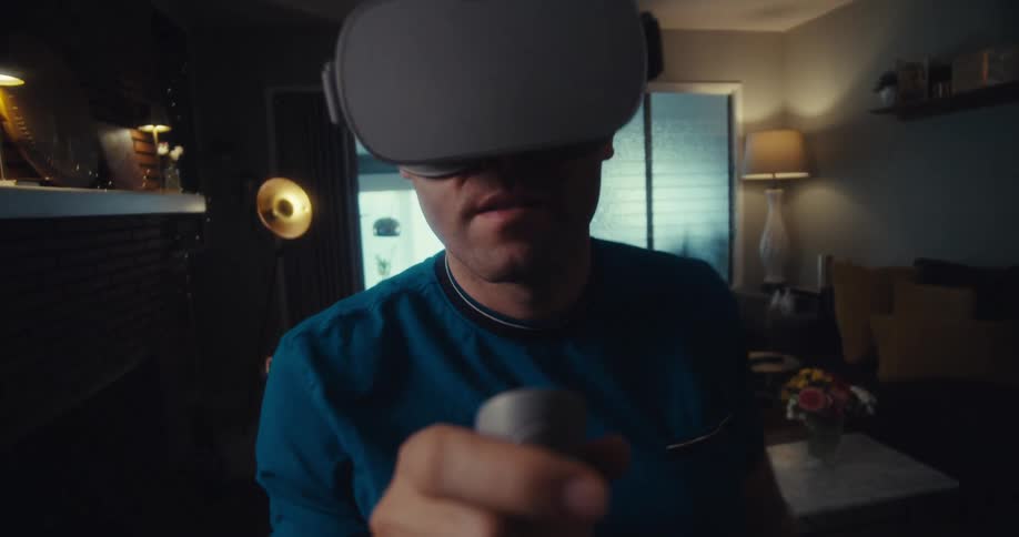 Man using virtual reality glasses and a remote control while standing in a living room