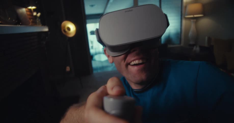 Man smiles while playing a game in his living room using a virtual headset