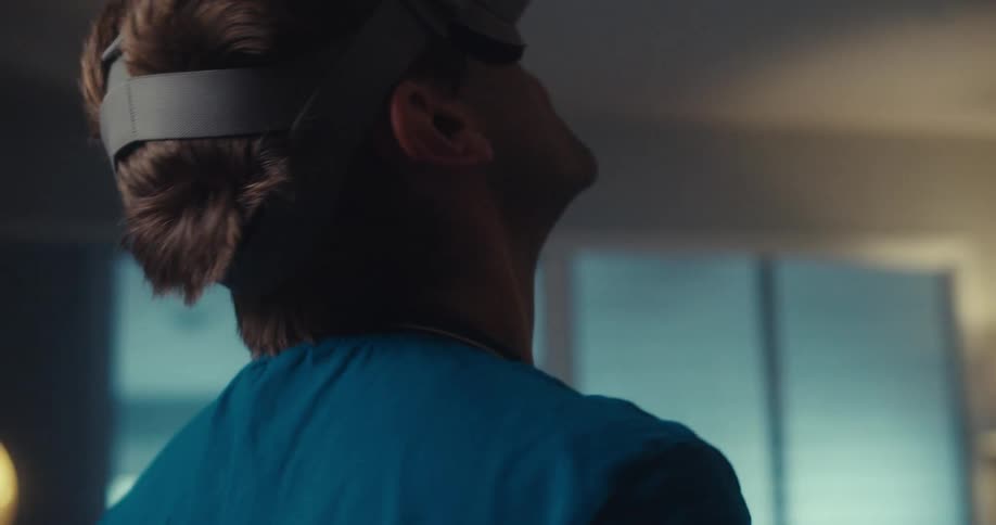 A young man wearing a vr headset slowly orbits in place while immersed in a virtual environment