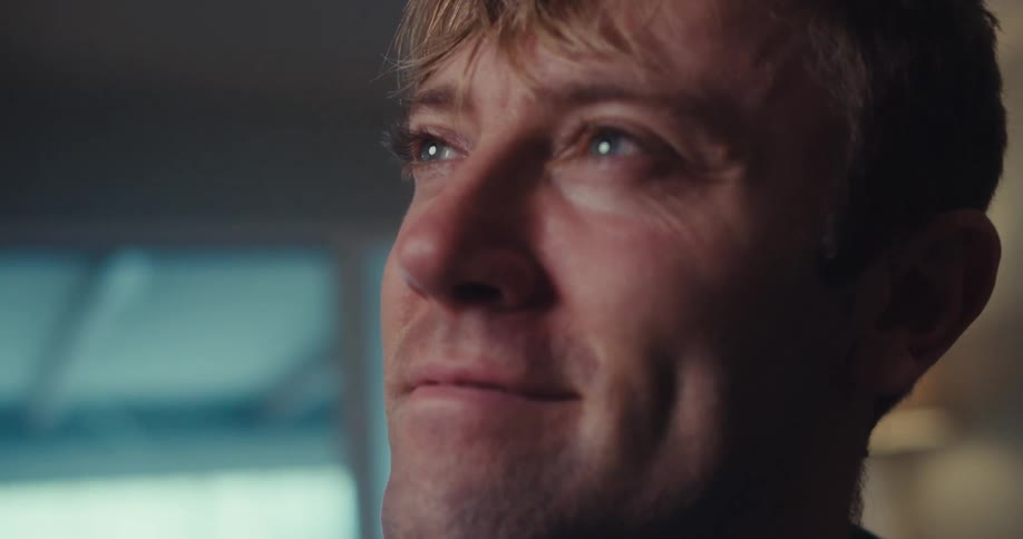 Closeup of a man smiling with lifted eyebrows as he daydreams or imagines something pleasant