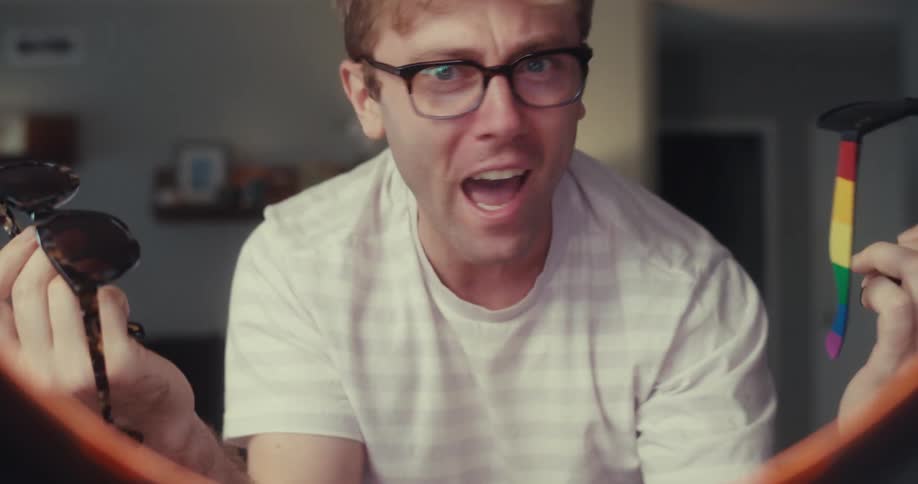 A man excitedly records himself holding up a pair of sunglasses toward the camera