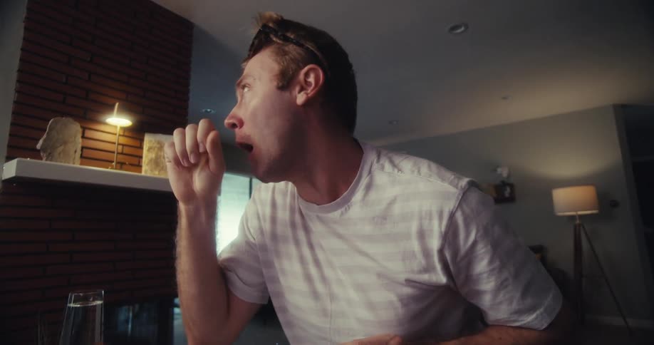 A man is recording a product video with sunglasses in a home setup using a ring light and camera