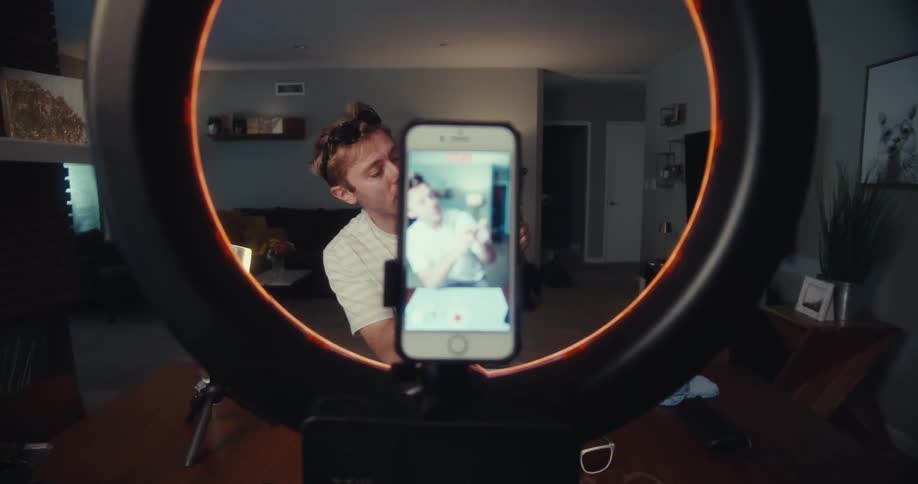 Man holding sunglasses and recording in front of a smartphone