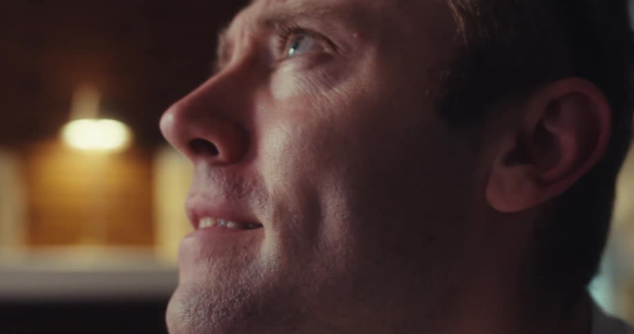 Man leans forward and looks up as he talks animatedly