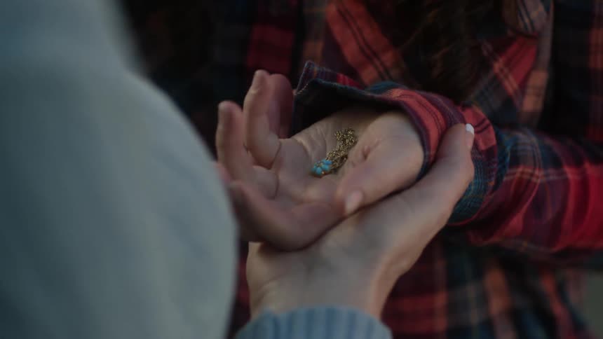 A woman places a necklace in another woman's hand