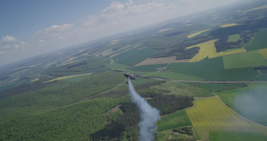 Small airplane emits smoke while heading towards the ground in the rural countryside during the daytime