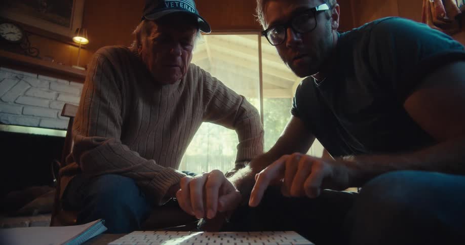 Younger man demonstrates a task on a computer to an elderly man during the daytime