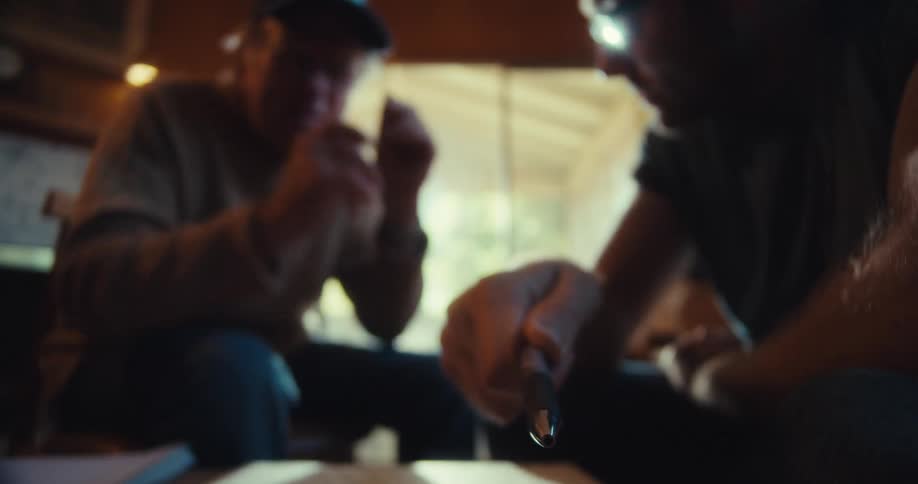 Man holding a pen and pointing in a direction while talking to an elderly man