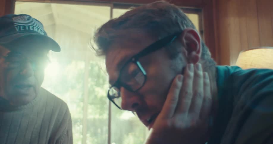 Elderly man talking to a young man sitting in a room