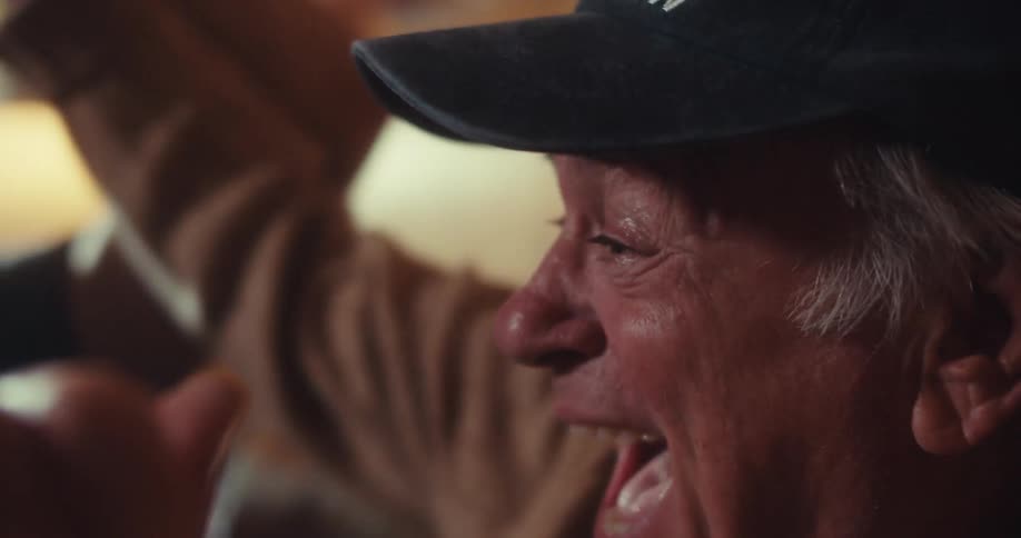 A father and son excitedly watch something on a smartphone laughing and highfiving in celebration