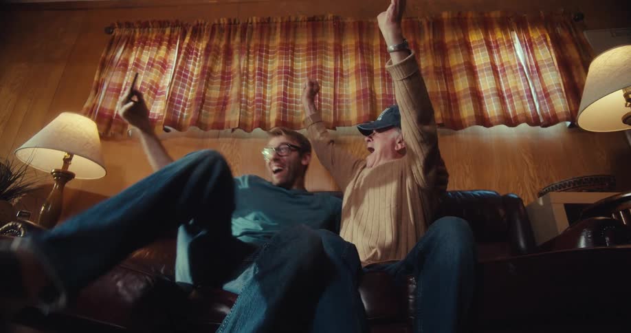 Grandfather and grandson hug and celebrate something they see on a phone