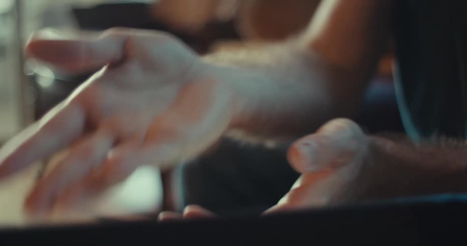A man is sitting and pointing at a laptop