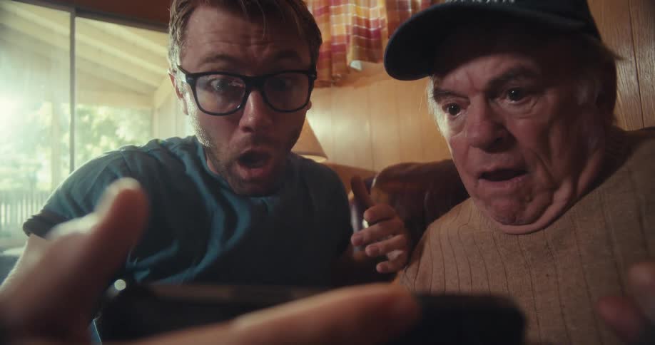 Grandfather and grandson react with frustration to what is happening on the phone the grandson is holding