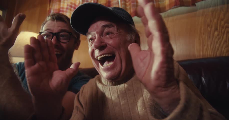 Two men clap and cheer at something on the cell phone