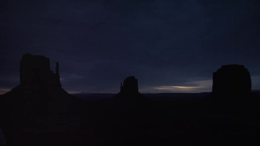 Large rock formations are silhouetted at dusk