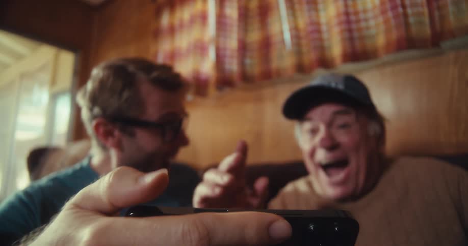 Two men are excited and high five as they watch something on a phone