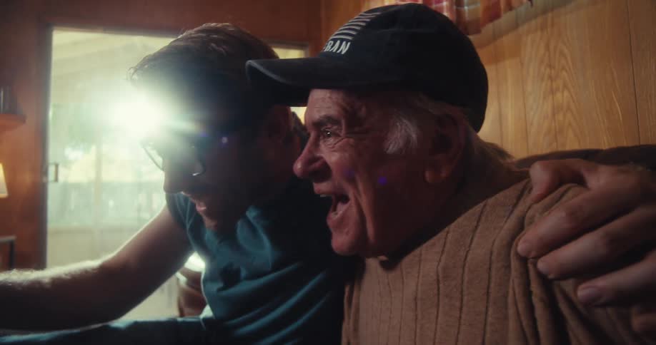 A father and son raise their arms in excitement over something they saw on a smartphone