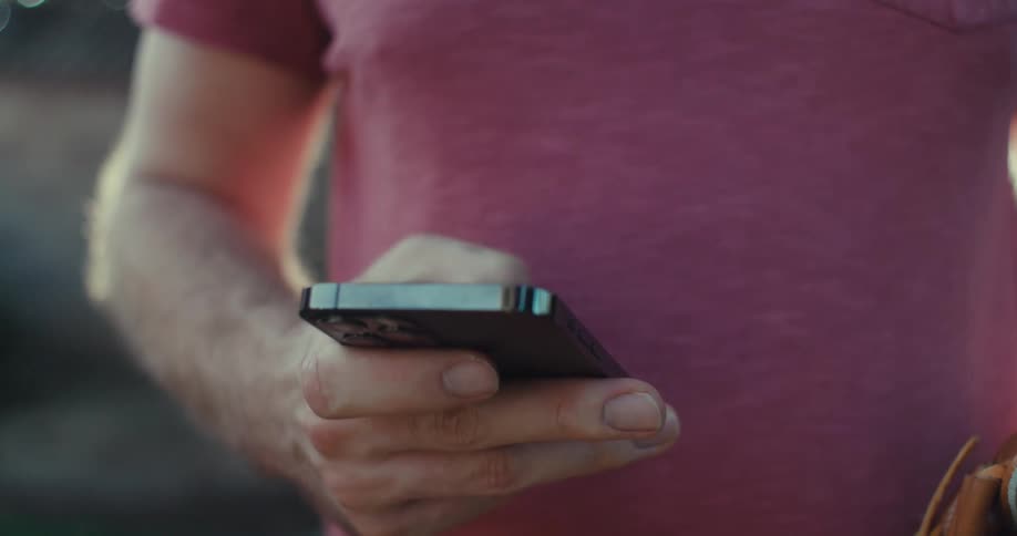 A man is typing on his cell phone outside