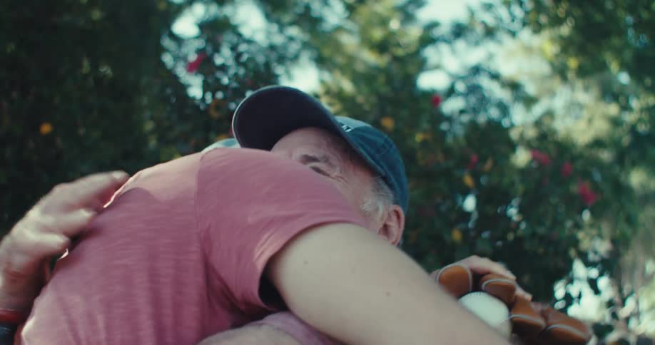 Elderly man and a man happily hug each other in a backyard with trees