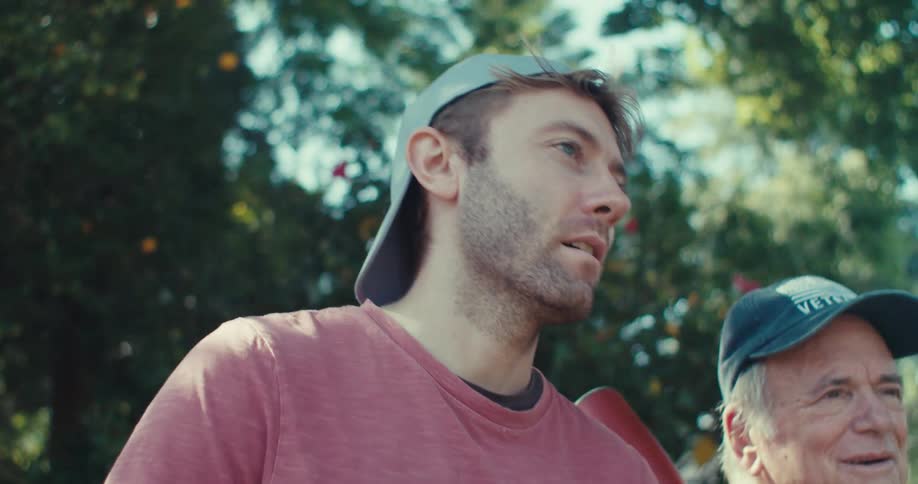 A young man and older man smile and talk before a backyard baseball game
