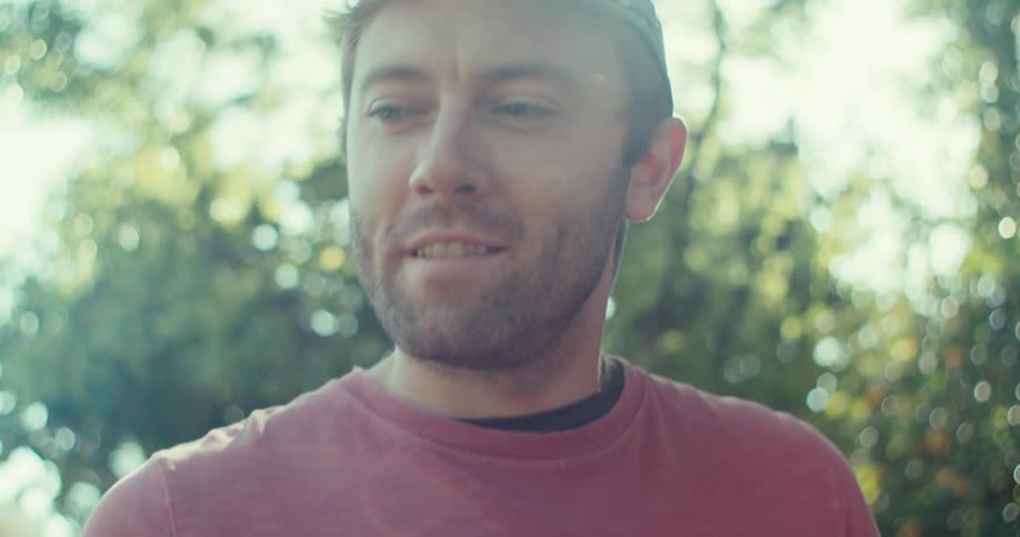 Man outdoors holding a baseball and talking