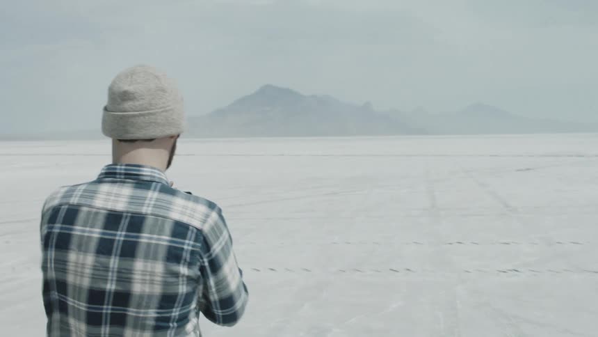 Man walks in the desert and takes pictures of mountains with smartphone