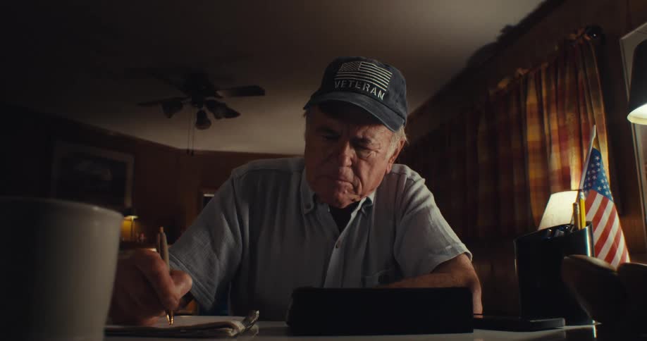 A man sitting with a cup of coffee is writing on paper