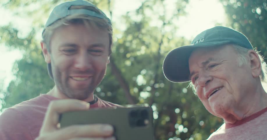 A footage of a man and an elderly man watching a content on a smartphone