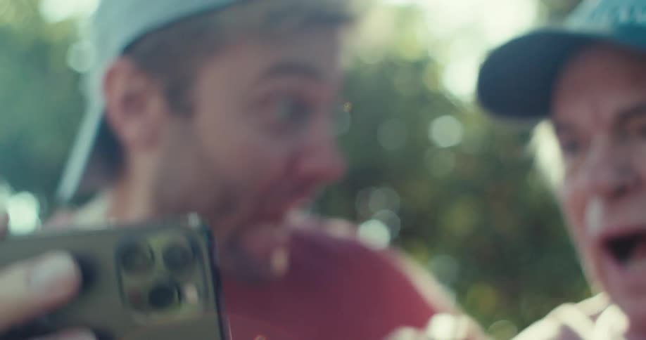 Two men look at a cell phone screen in surprise