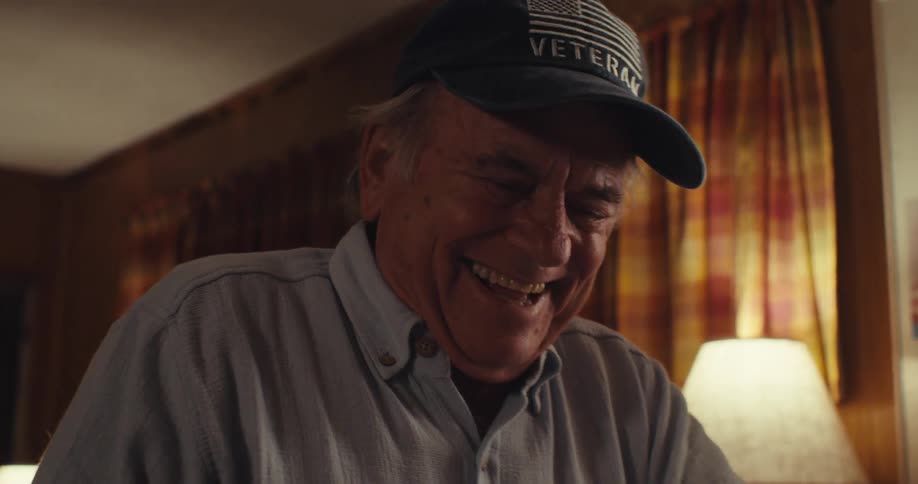 Elderly man taking off his glasses laughing and writing in a notebook