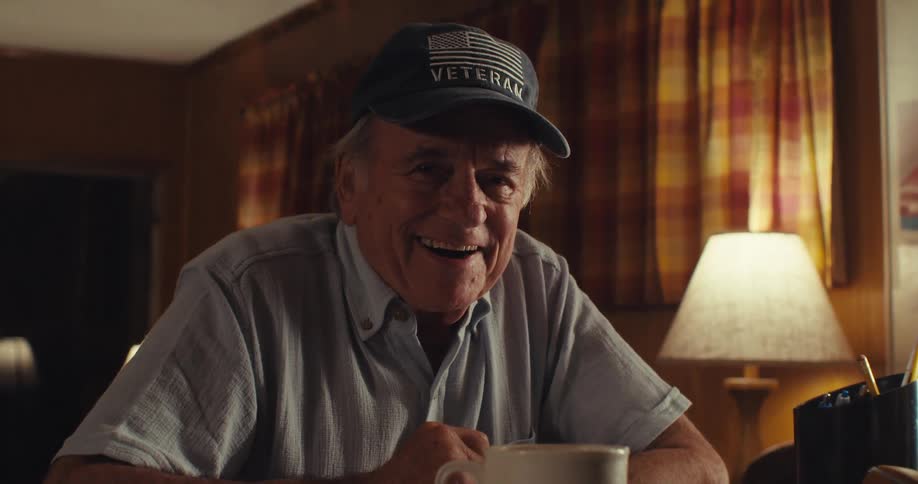 Elderly man sitting at a table with happy facial expression