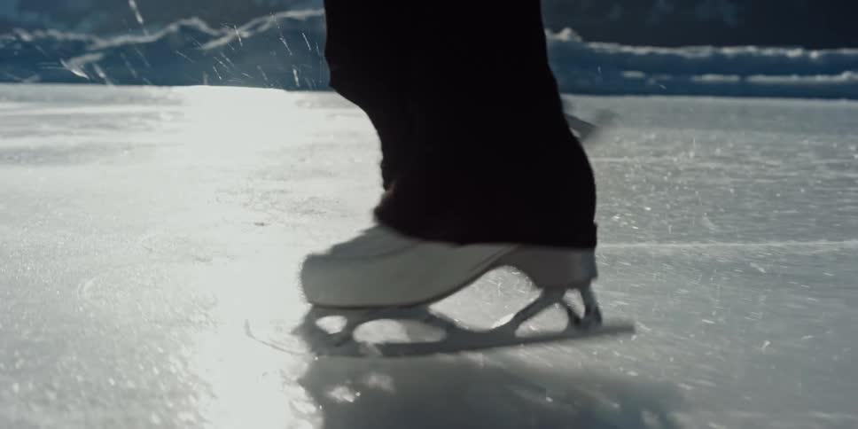 Skates glide across the shining ice as frozen sparks scatter around