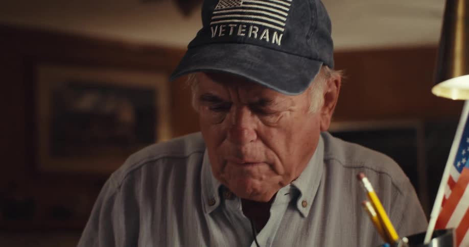 Elderly man sitting down taking off his glasses and putting them back on