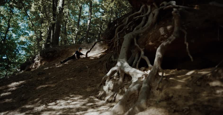 Boy slides down a steep hill in the forest on the sides of his feet