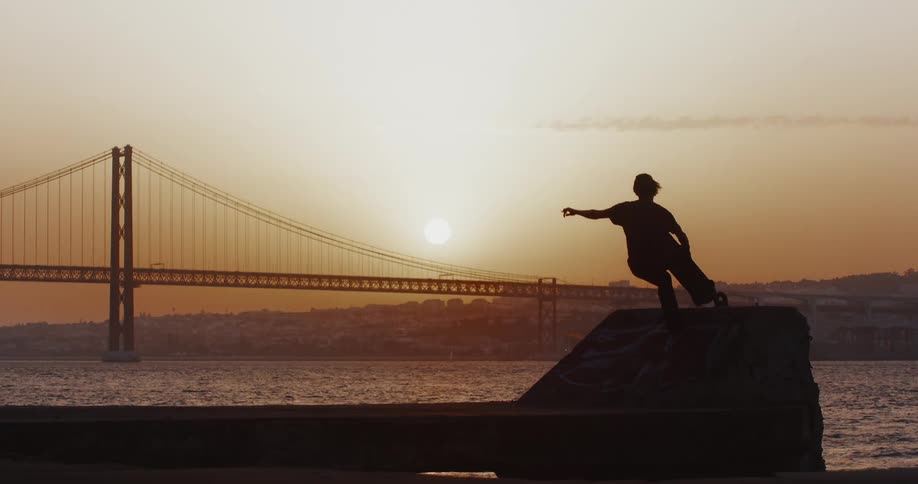 A teenager does a jump on his skateboard by the water