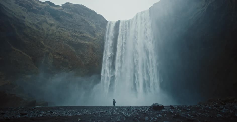 A person stands near the bottom of a waterfall