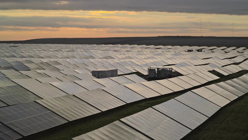 A large solar farm with battery and inverter visible at dawn