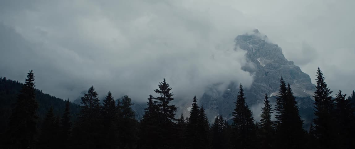 Mist enveloping a mountain with a forest beneath it during winter