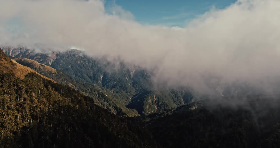 Low lying clouds partially obscure forested mountains on an autumn day