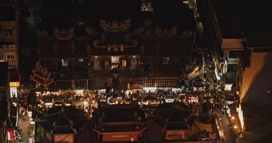 People walk around a traditional setting located near apartment buildings at night