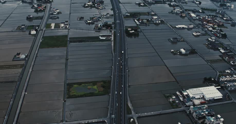 Aerial view of a highway with vehicle traffic and scattered houses on divided land