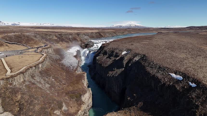 A canyon with a stream flowing beneath it under the bright midday sun