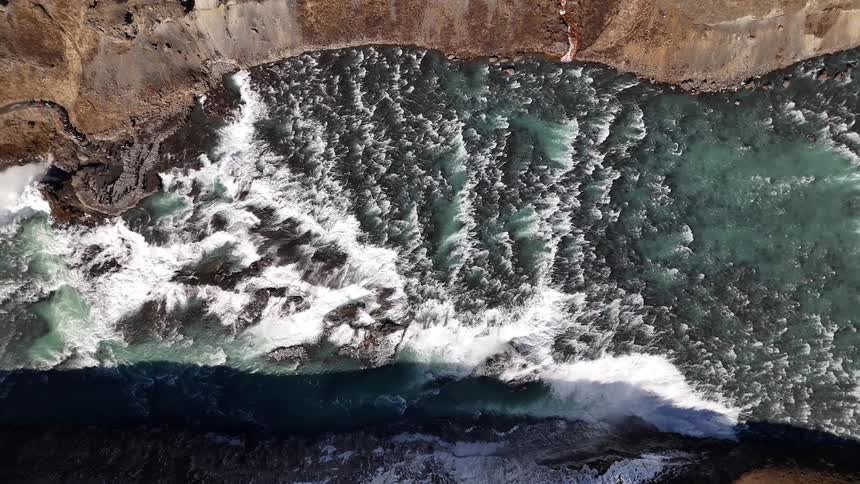 Rapids in a river cutting through the mountains on a sunny day