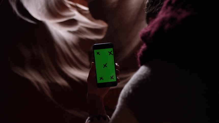 A person holding a phone where the screen is green and has x's on it