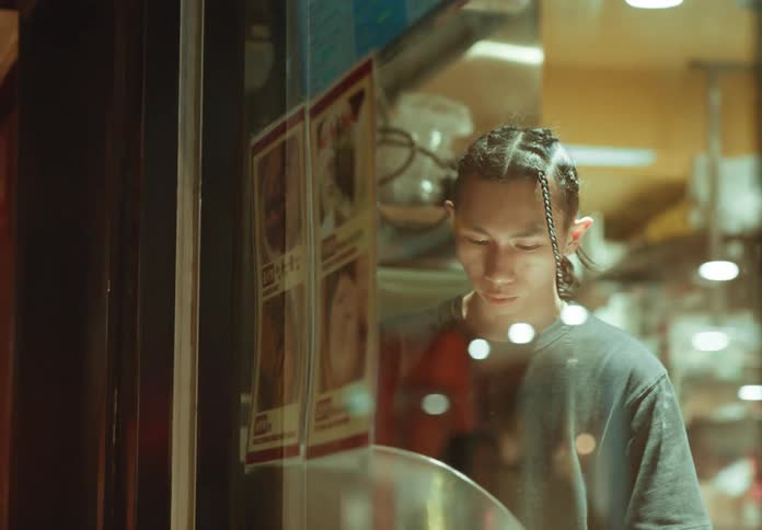 The reflection of two people shows in the window of a restaurant as a worker looks outside