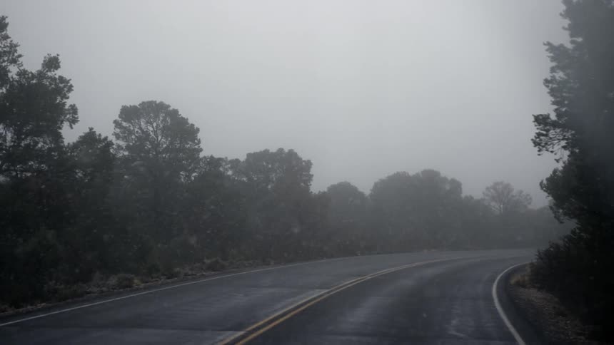 A vehicle drives down a road during a storm